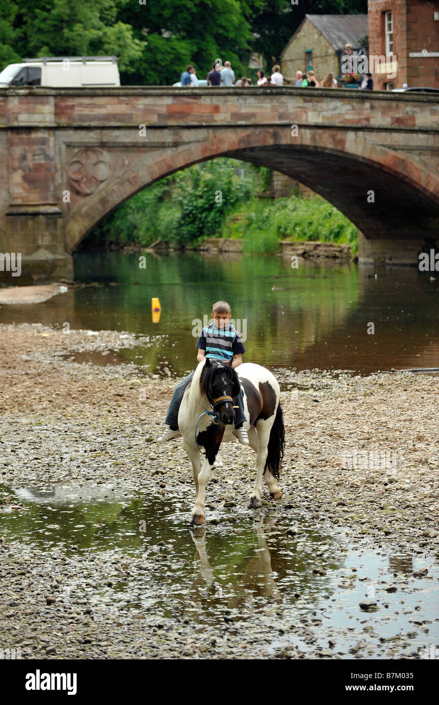 A Romany boy rides bareback on a horse in the River Eden at Appleby in Westmoreland Appleby gypsy horse fair Stock Photo