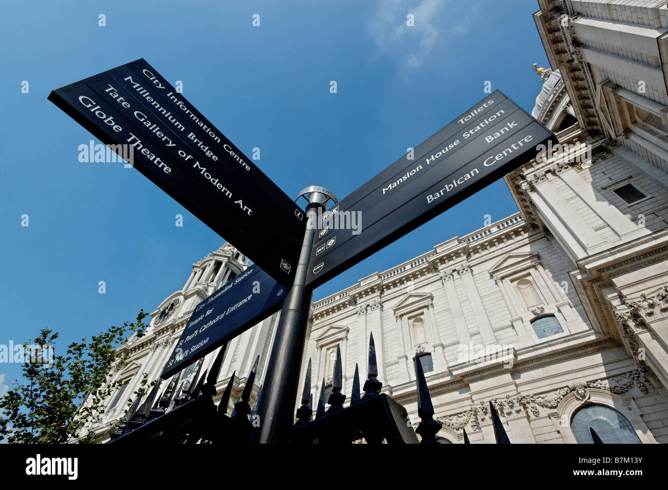Looking up at St Pauls Cathedral and a sign for various tourist attractions Stock Photo