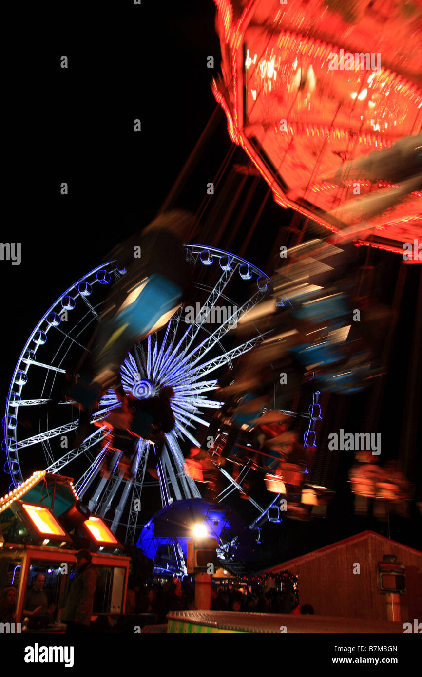 Illuminated traditional merry go round style fairground rides and big wheel, Winter Wonderland, Hyde Park, London Stock Photo
