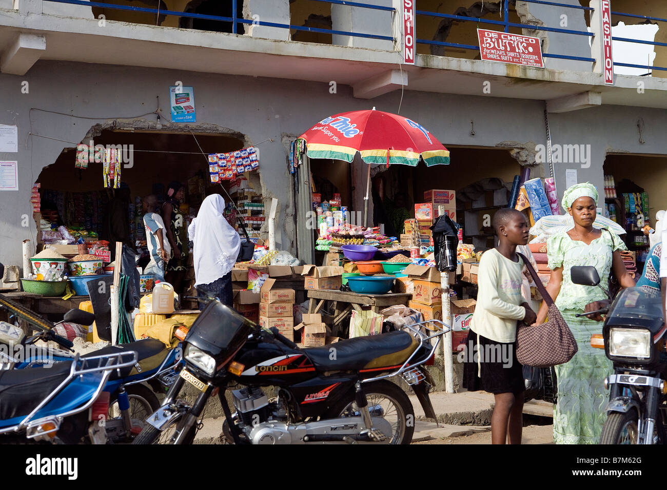 A busy row of shops in Poka, Epe, Lagos, with people outside and motorbikes parked Stock Photo