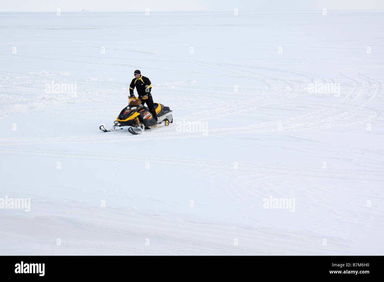 A young man rides on a snowmobile on a frozen Lake Erie in Ohio USA US lifestyle daily life all only white full background  a lot of snow hi-res Stock Photo