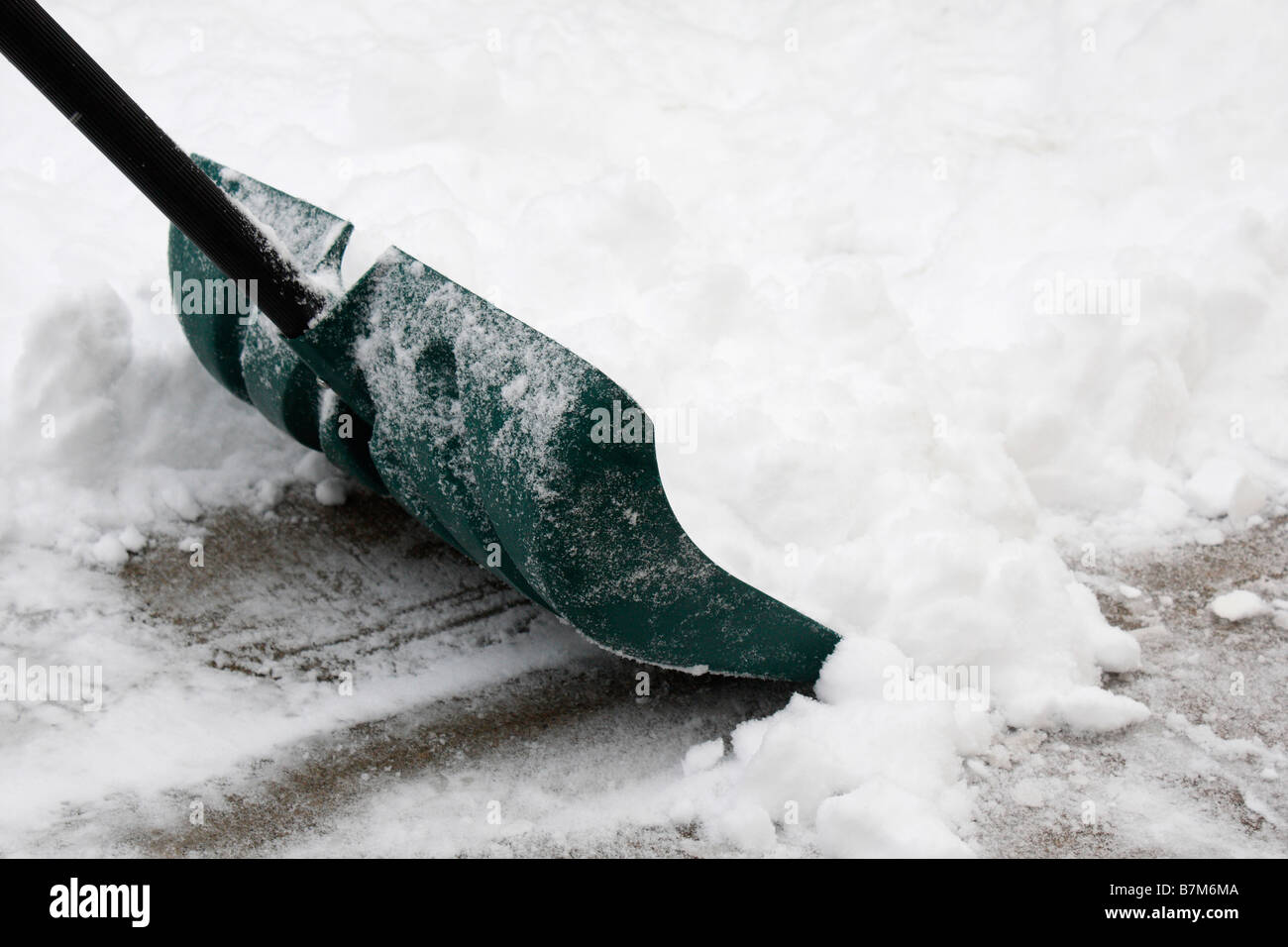 The snow shovel shovels snow from the sidewalk winter hi-res Stock Photo