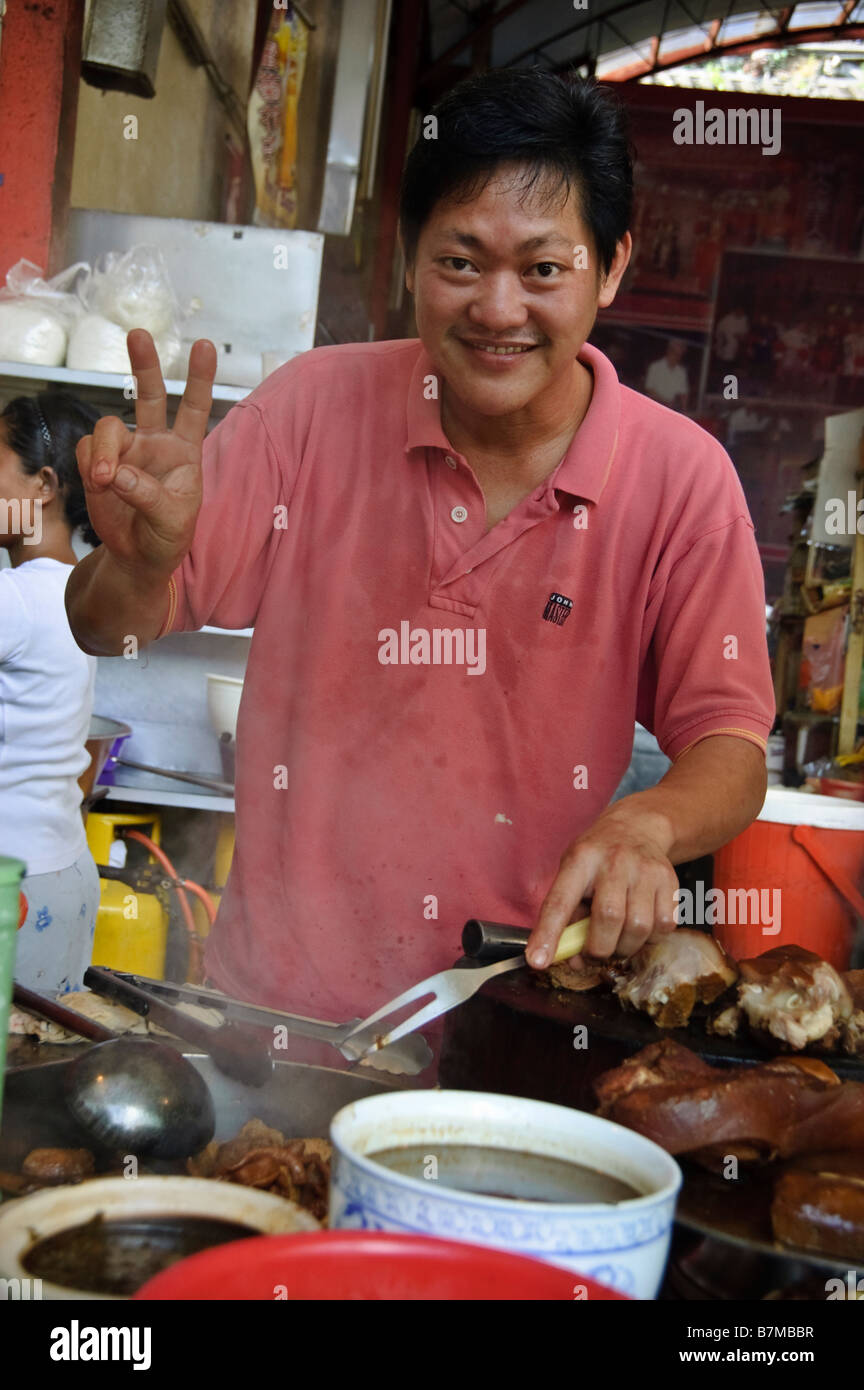 Man cooking pork poses for the camera in Kuching, Malaysia Stock Photo