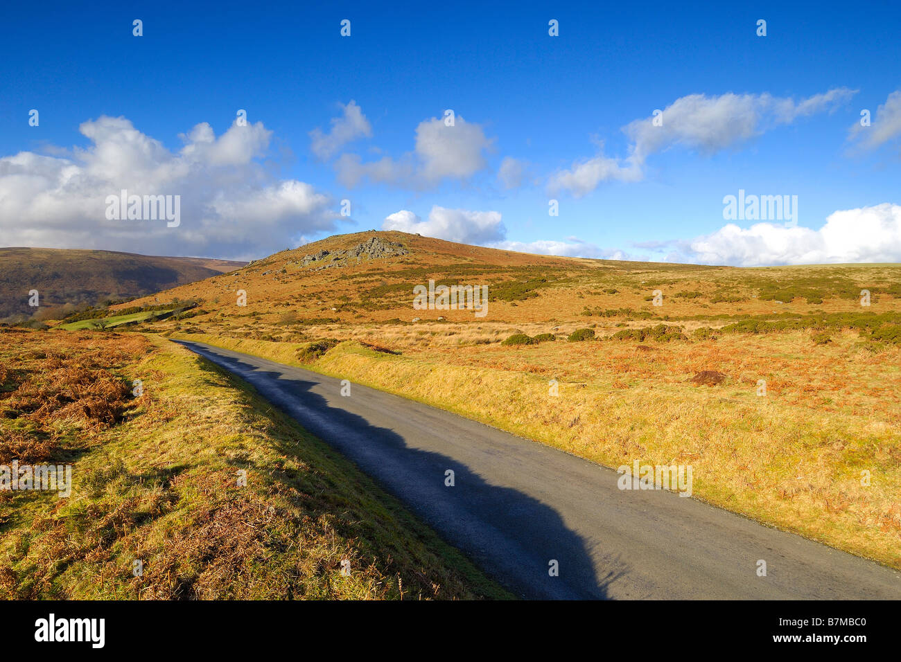 A narrow single track country road near Bonehill Rocks on Dartmoor with Chinkwell Tor in the middle distance Stock Photo