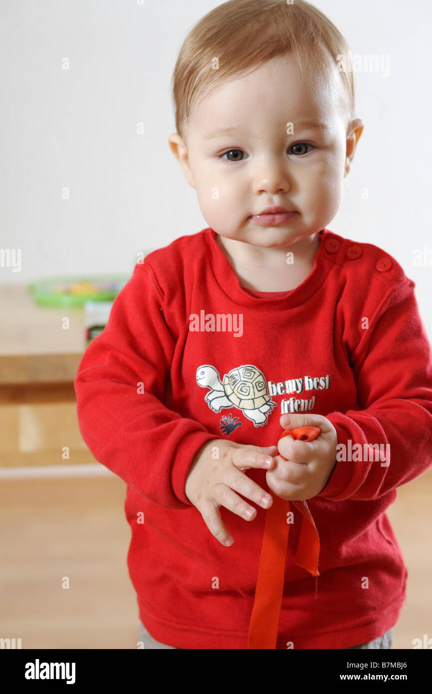 Child (12-18 month) holding toys, looking at the camera. Stock Photo