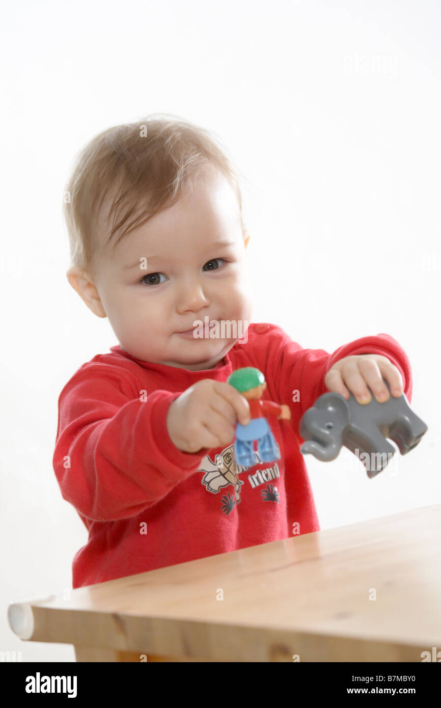 Child (1218 months) playing on table. Looking into the camera, raising