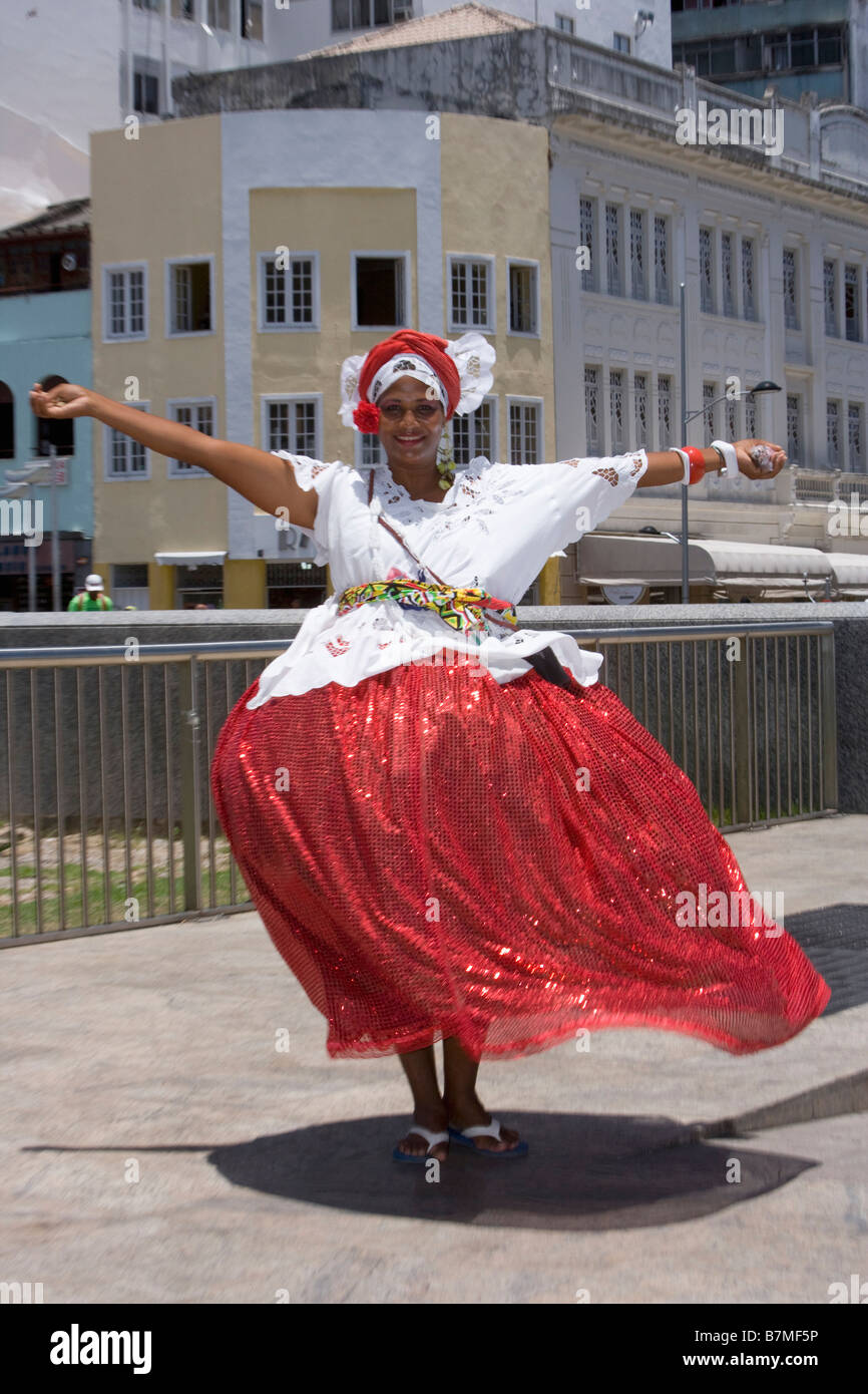 Girl wearing Brazilian national dress of white shirt and bright pink skirt dancing for tourists Stock Photo