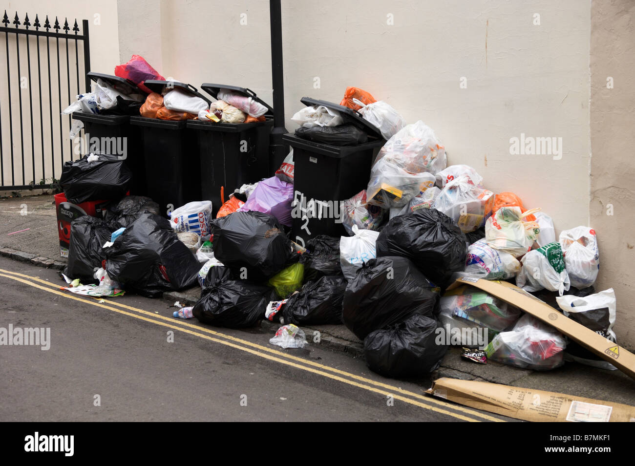 Domestic wheelie bins and bags piled waiting collection on street Stock