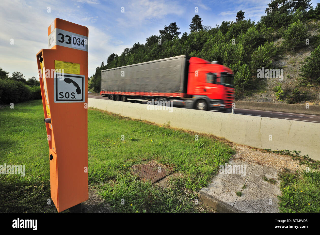 Emergency telephone on a French autoroute, with a lorry passing. Motion blur on the lorry. Stock Photo
