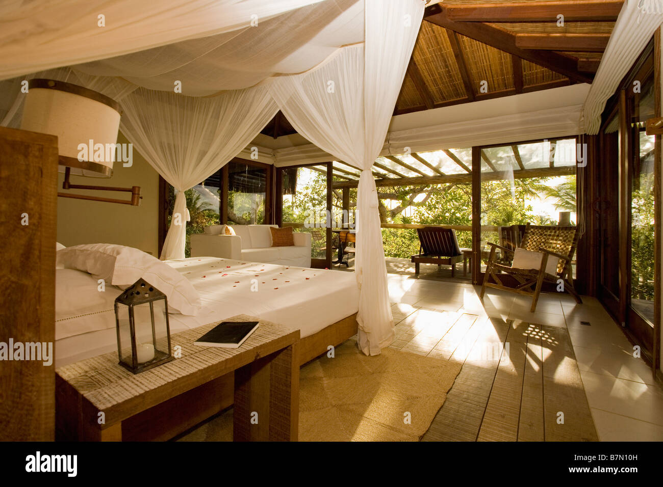 White Linen And Mosquito Drapes On Large Bed In Bedroom In