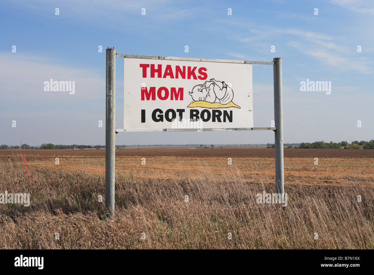 A sign in a rural Kansas field showing a baby and reads:   'Thanks Mom I Got Born' Stock Photo