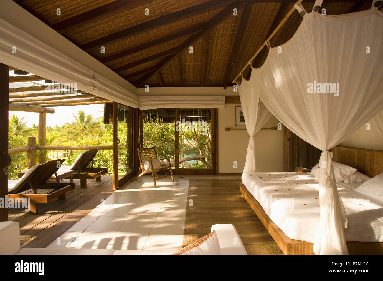 White Drapes On Simple Wooden Bed In Openplan Bedroom And Living