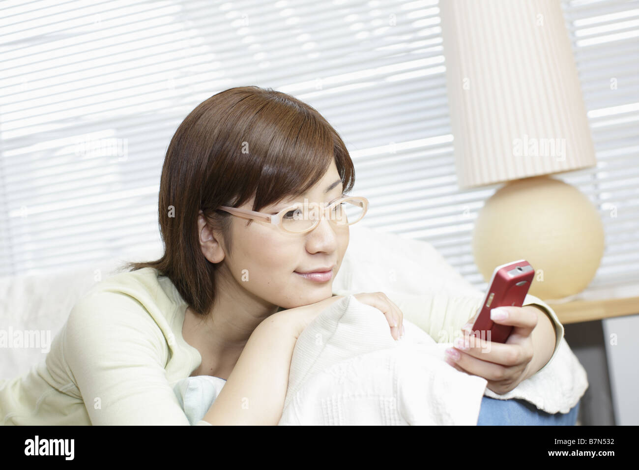 Woman Lying on a Sofa Holding a Cell-Phone Stock Photo - Alamy