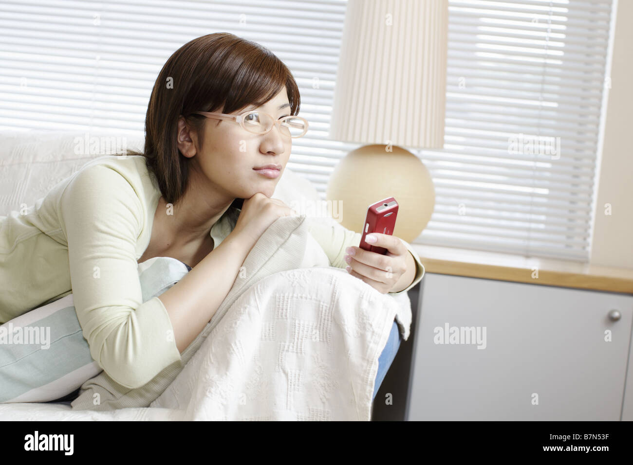 Woman Lying on a Sofa Holding a Cell-Phone Stock Photo - Alamy