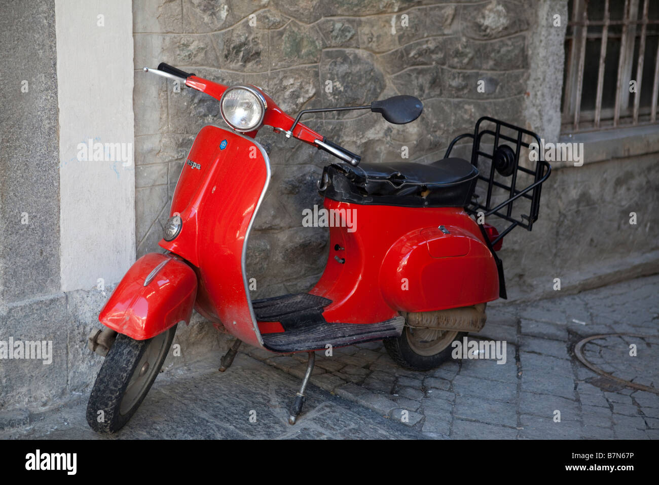 Red Vespa scooter parked in a narrow street in Bormio, Italy Stock Photo