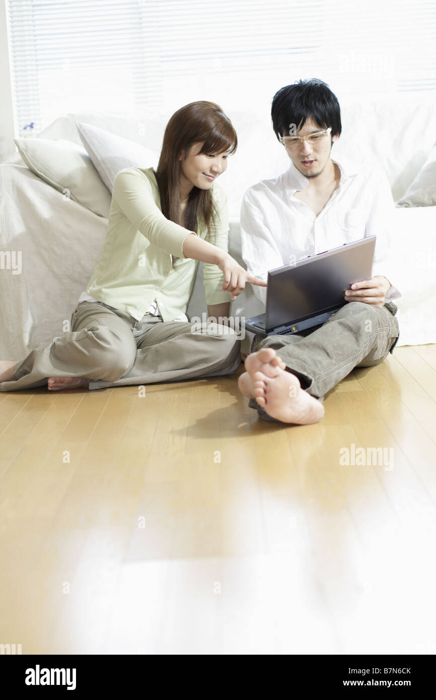 Smiling Couple Sitting on Floor With Laptop Stock Photo - Alamy