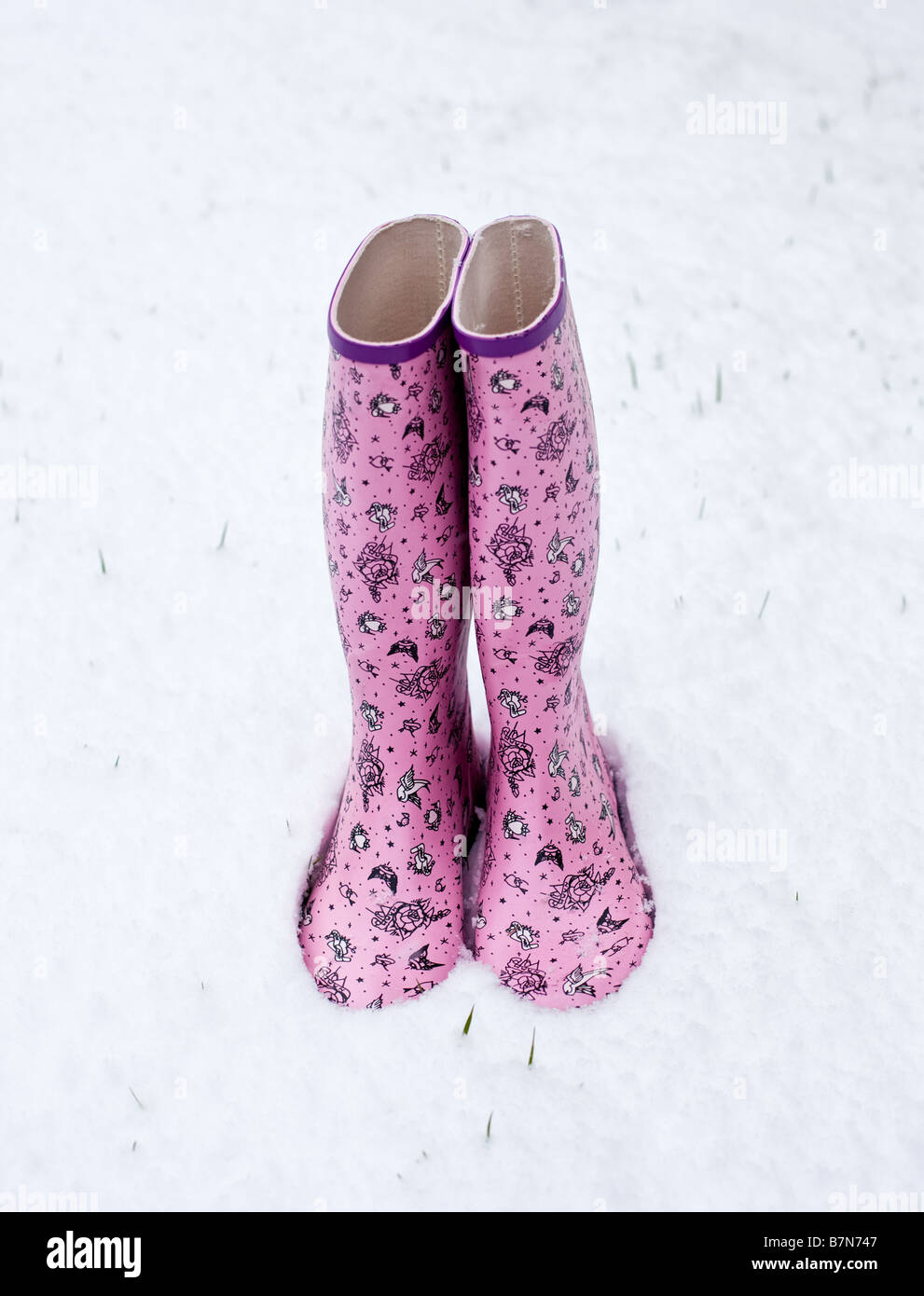 Colourful patterned wellington boots in snow in winter Stock Photo