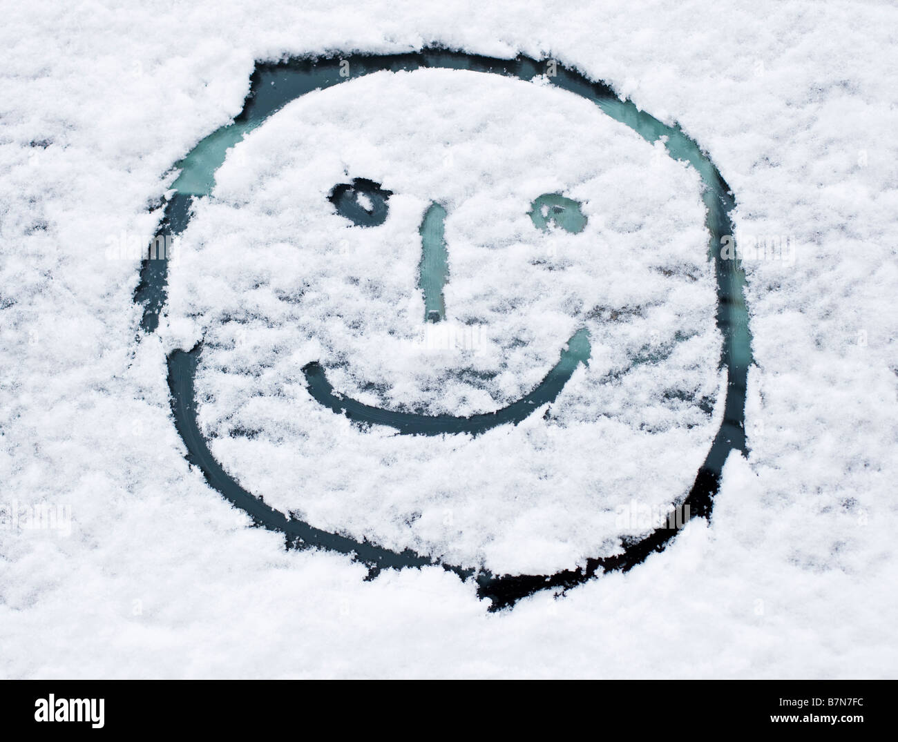 Winter snow - Smiley face drawn in fresh snow on a car windscreen Stock Photo