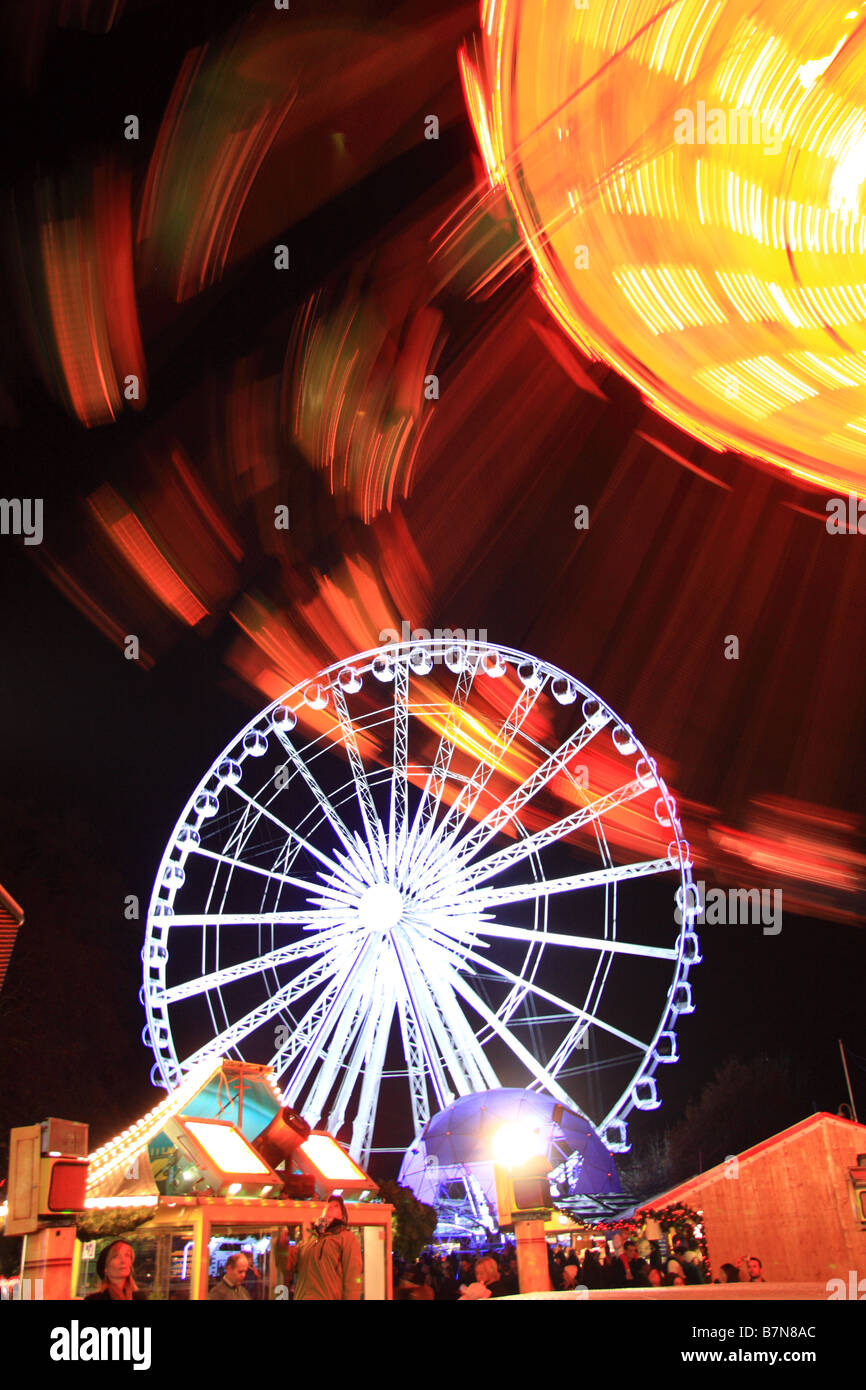 Illuminated big wheel & merry go round style fairground rides at Winter Wonderland, Hyde Park, London Stock Photo