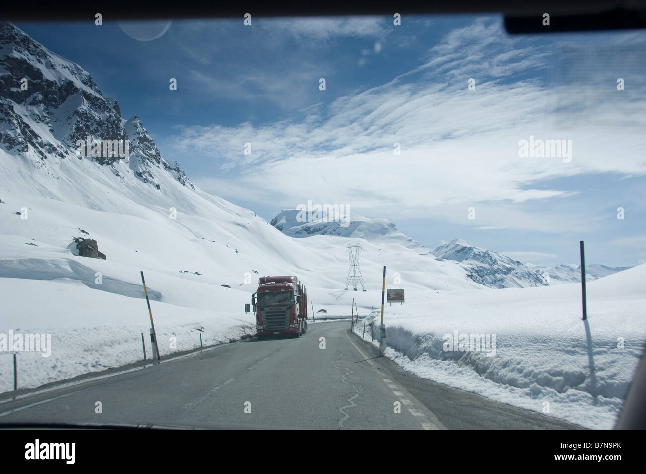 Truck on the snow covered Julier Pass, photographed through windscreen of car. Swiss Alps, Graubunden. Stock Photo