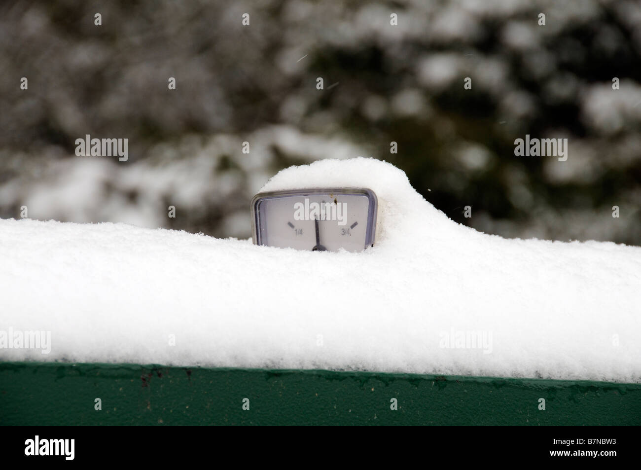 Oil fuel guage on top of a heating oil tank covered in snow England UK Stock Photo