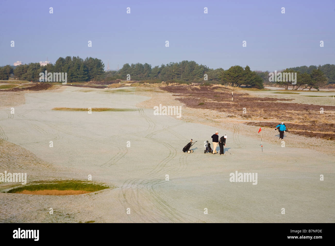 Three golfers playing golf in winter when the ground and golf course is