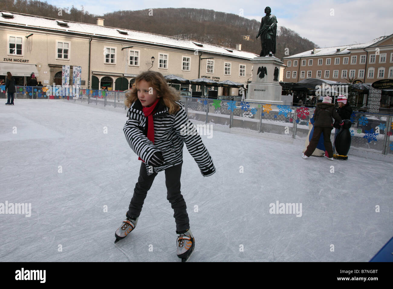 People skating on the skating ice rink at Mozartplatz with the monument to Mozart in the historic centre of Salzburg, Austria. Stock Photo
