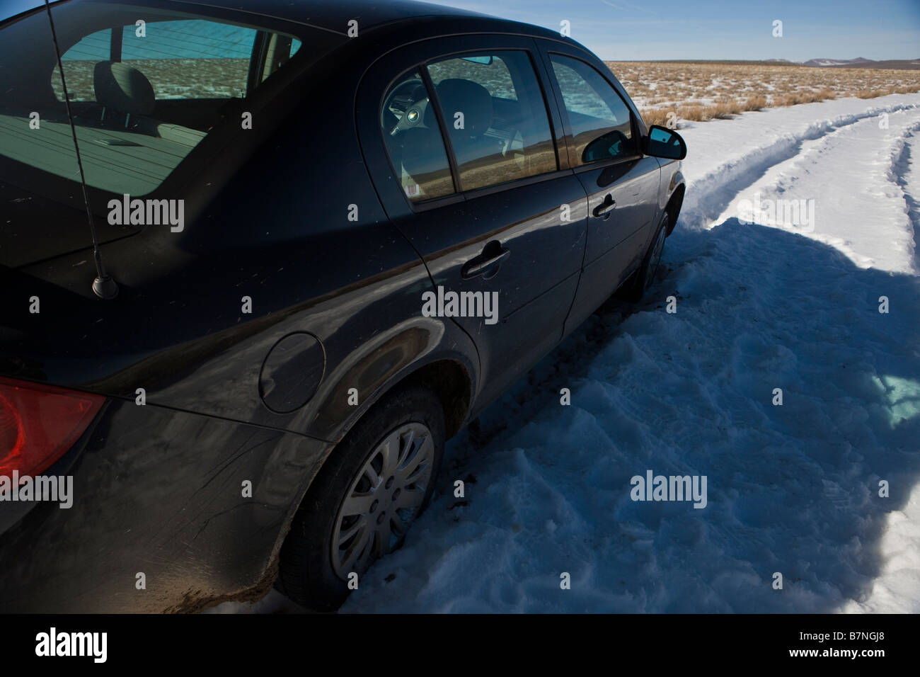 A black Chevrolet rental car is trapped on a snowy road next to