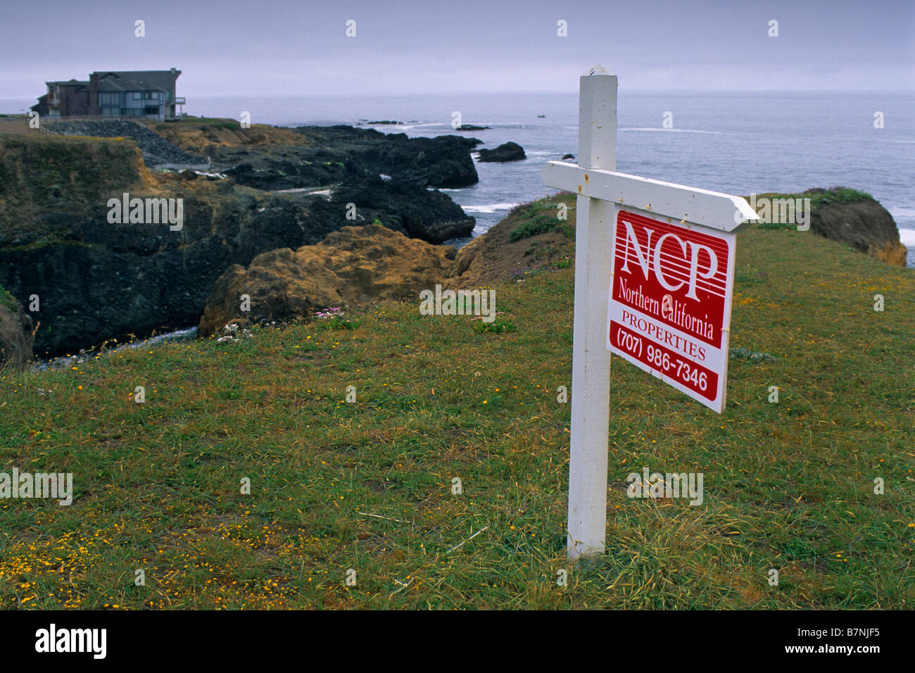 Real Estate For Sale sign on vacant lot property near coastal cliffs