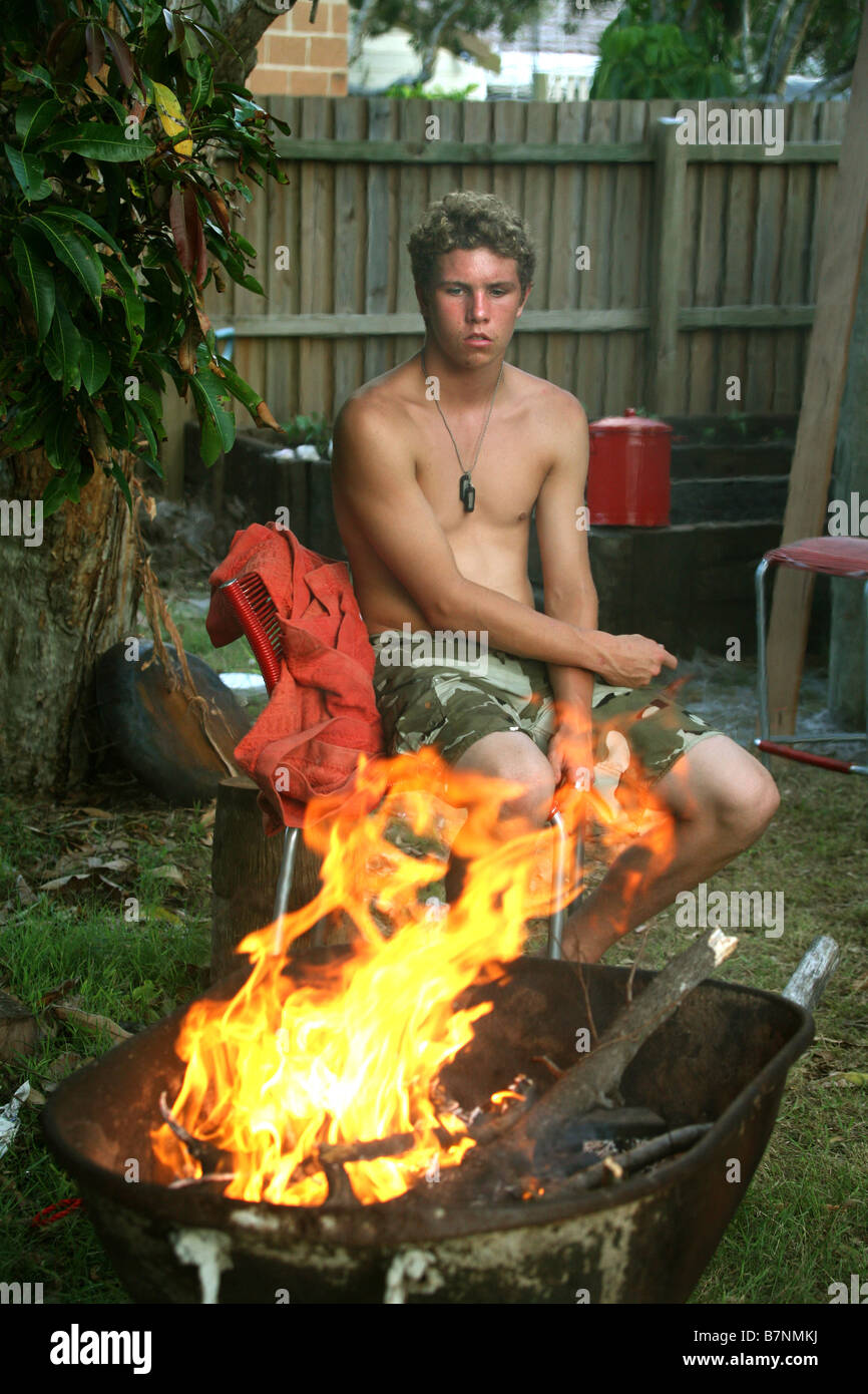 A young teen boy is mesmerized by a backyard fire Stock Photo