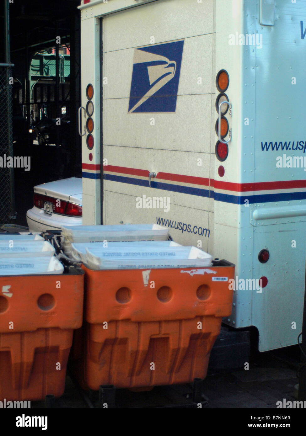 Full orange mail bins lined up and waiting to be loaded onto a USPS mail truck in New York City. Stock Photo