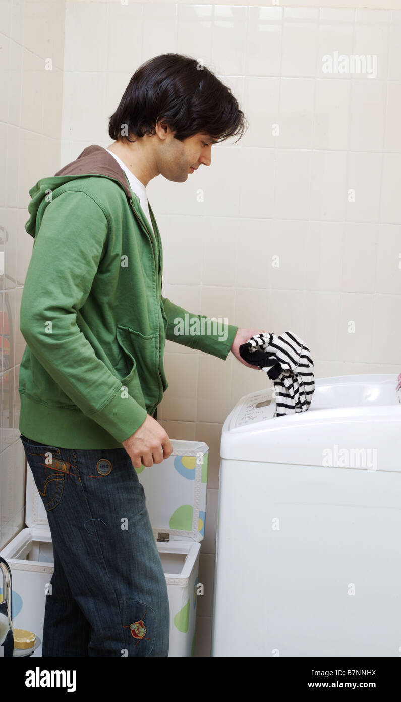 Young man loading clothes in a washing machine Stock Photo Alamy