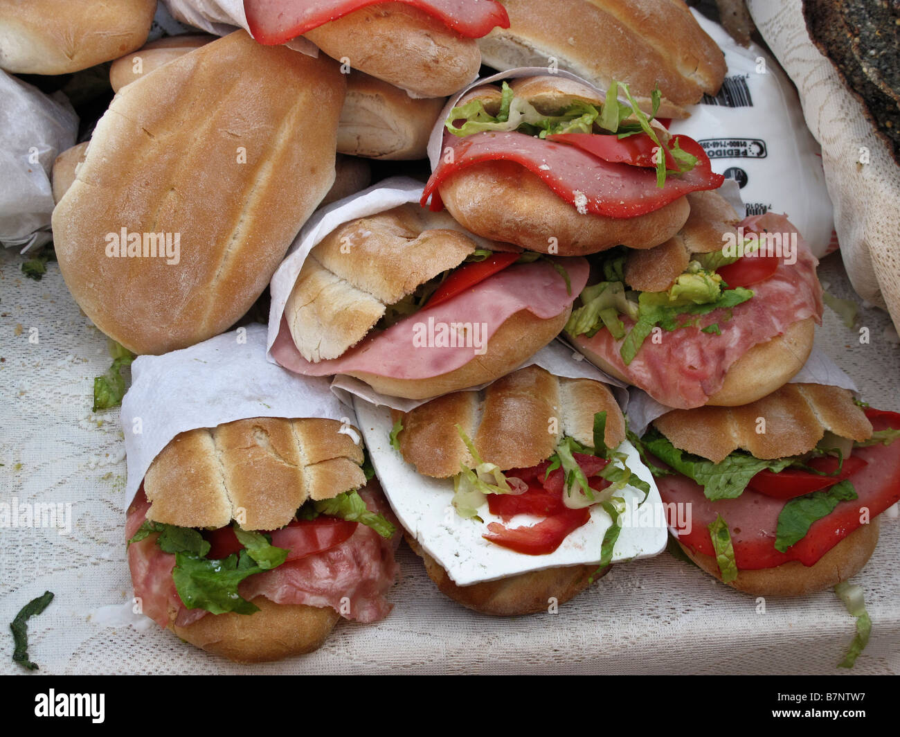 pile of mouth watering meat sandwiches garnished with lettuce & tomato for sale at an outdoor vendor in Mexico City, DF, Mexico Stock Photo