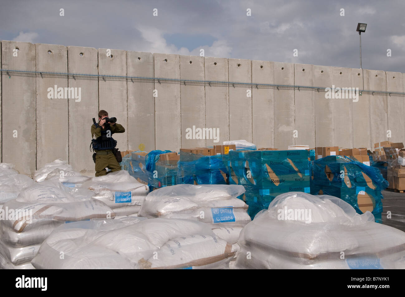 An Israeli soldier photographing sacks of food donated by UNRWA and WFP prepared to enter Gaza strip at the Kerem Shalom border crossing Israel Stock Photo