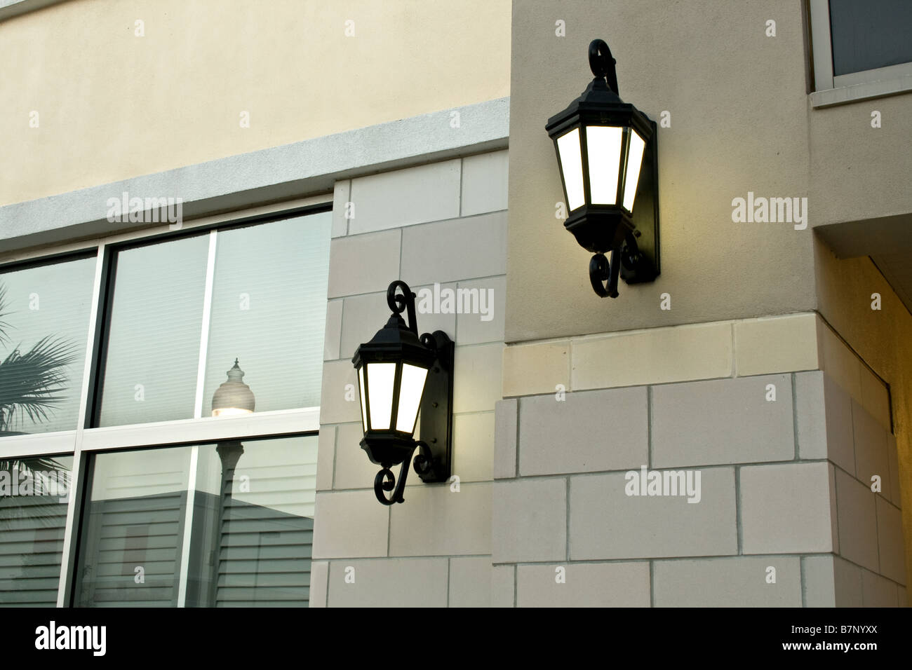 Two old fashioned black lamps on the side of a brick building by a window Stock Photo