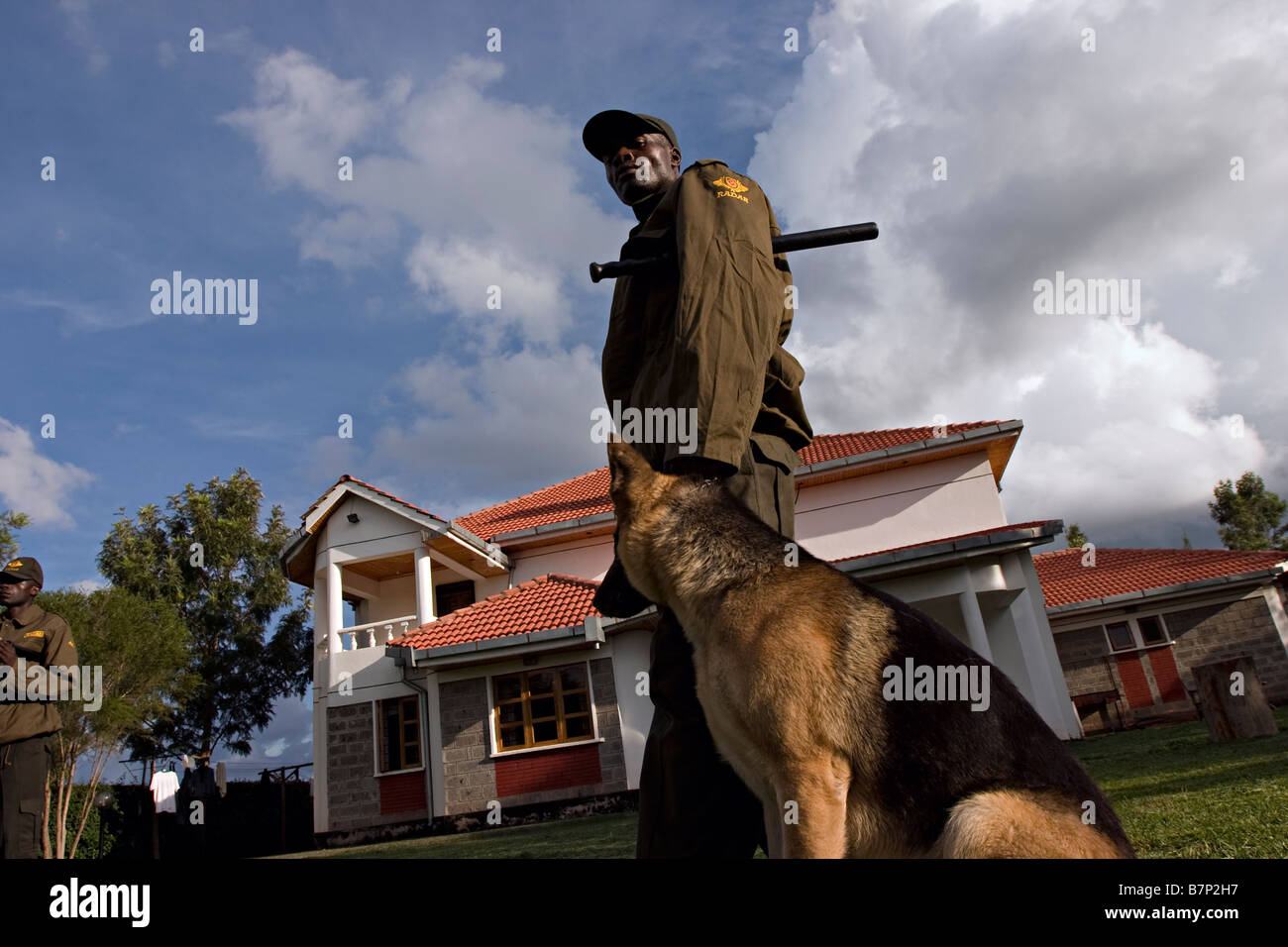 A security guard patrolling the compound of a house with a trained