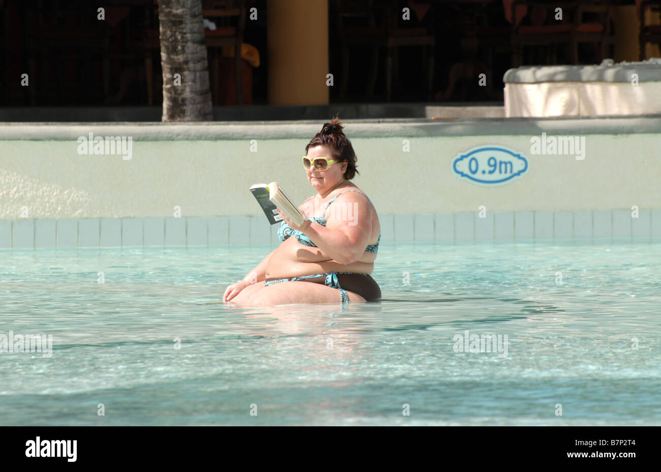 Lady reading a book in a swimming pool Stock Photo