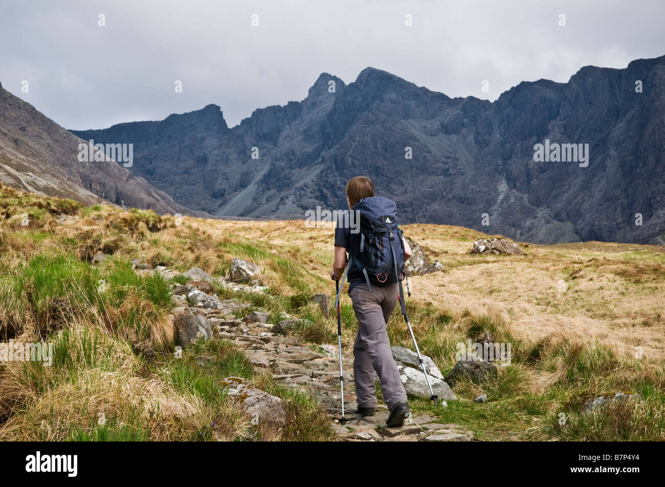 Female hiker hikes on stone path from Glenbrittle leading to Black Cuillins, Isle of Skye, Scotland Stock Photo