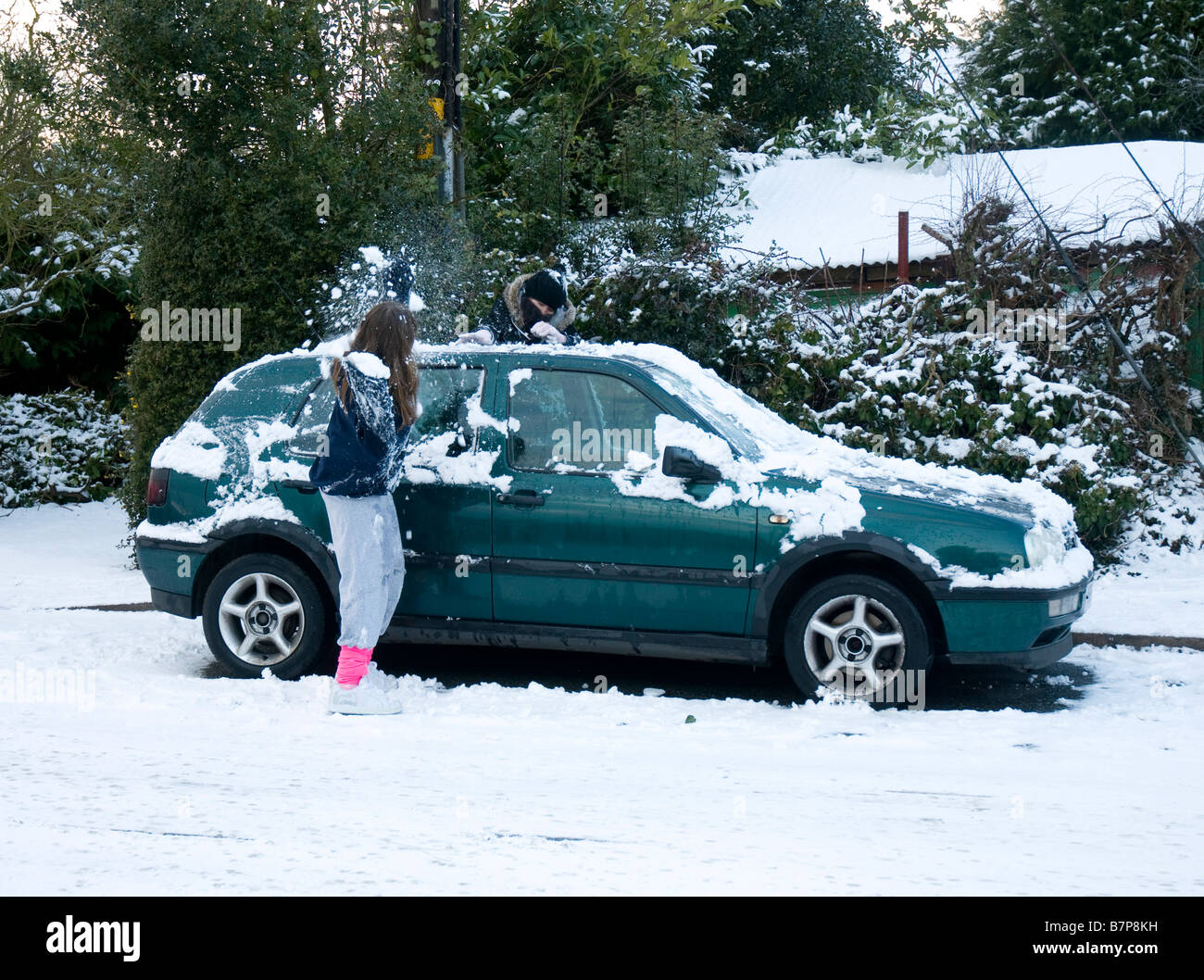 Two girls enjoying a snowball fight next to a VW Golf Stock Photo