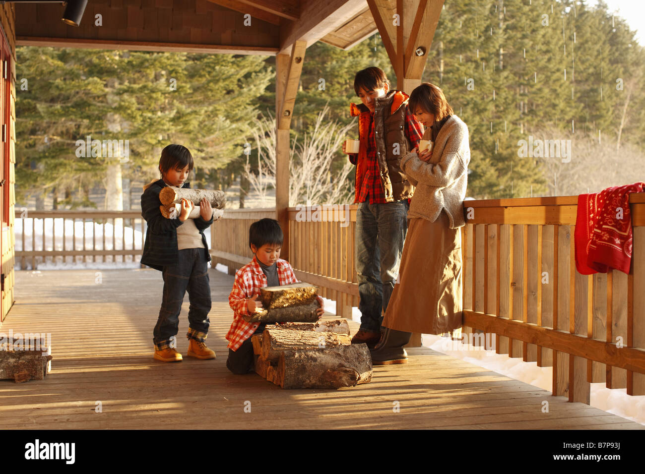 Children carrying firewood and parents standing by watching Stock Photo ...