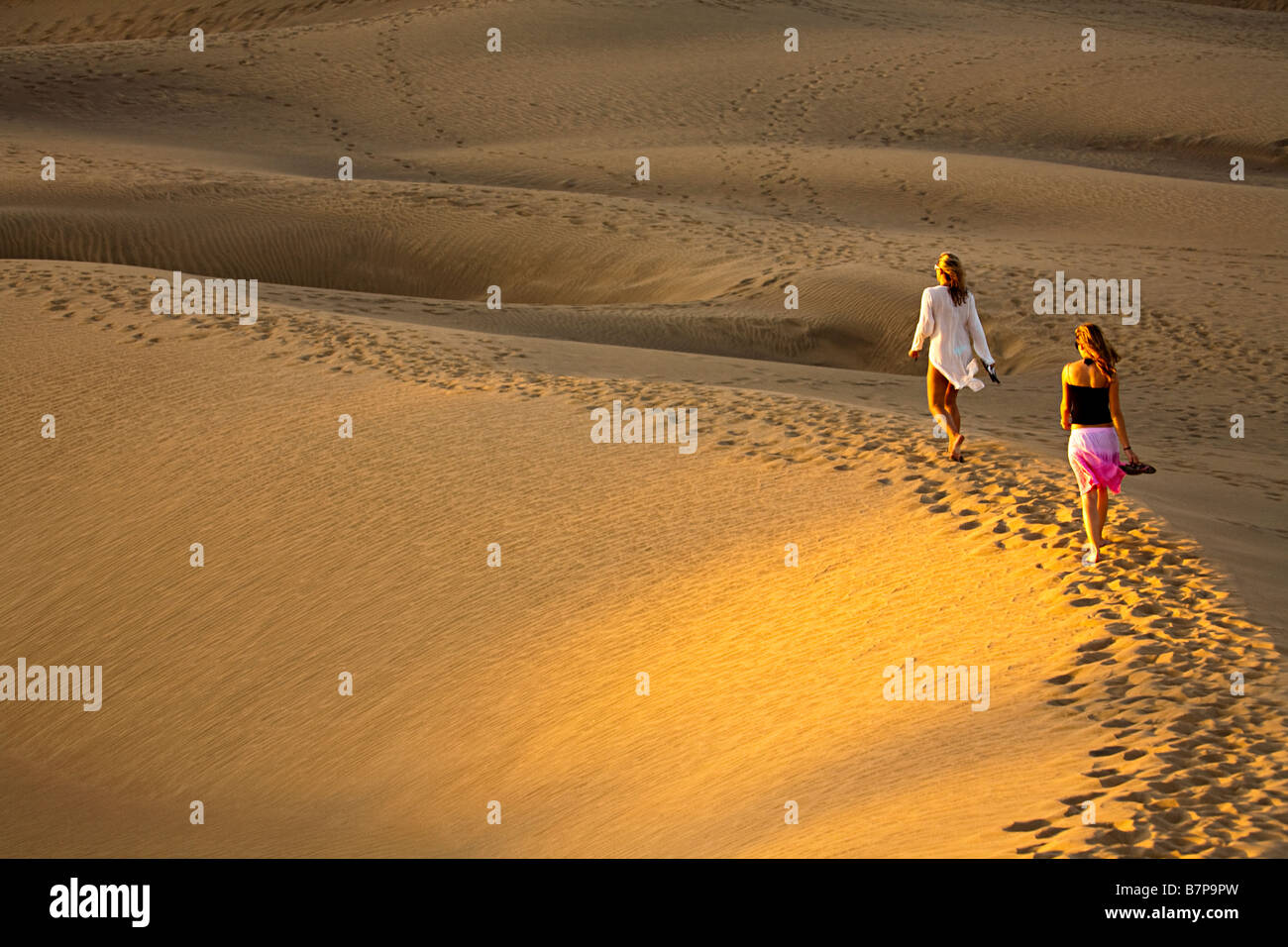 Two women walking barefoot in dunes Maspalomas Gran Canaria Spain Stock Photo