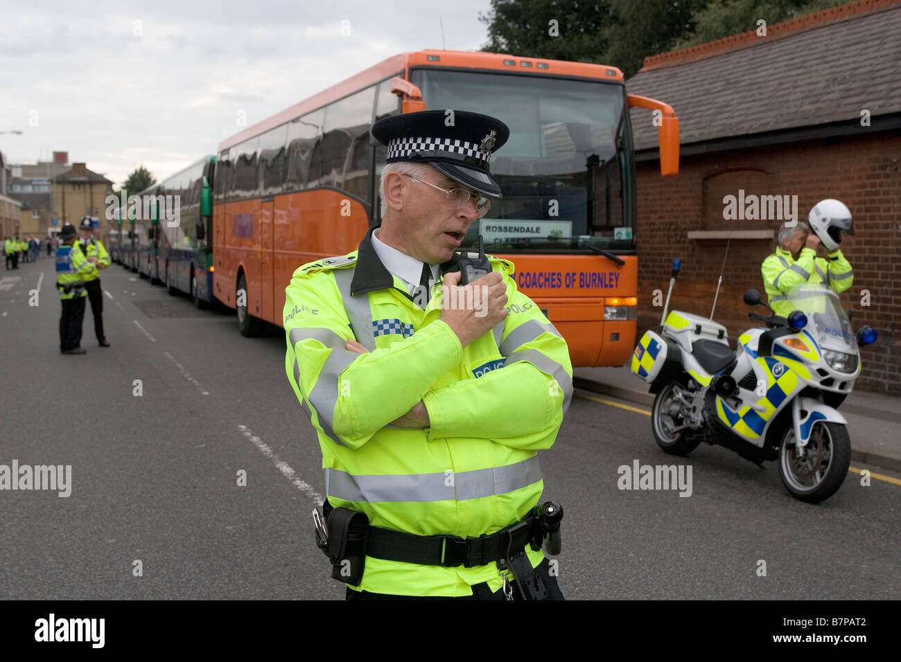The Commandant of Hertfordshire Special Constabulary talks on his radio before letting coaches carrying fans leave. Stock Photo