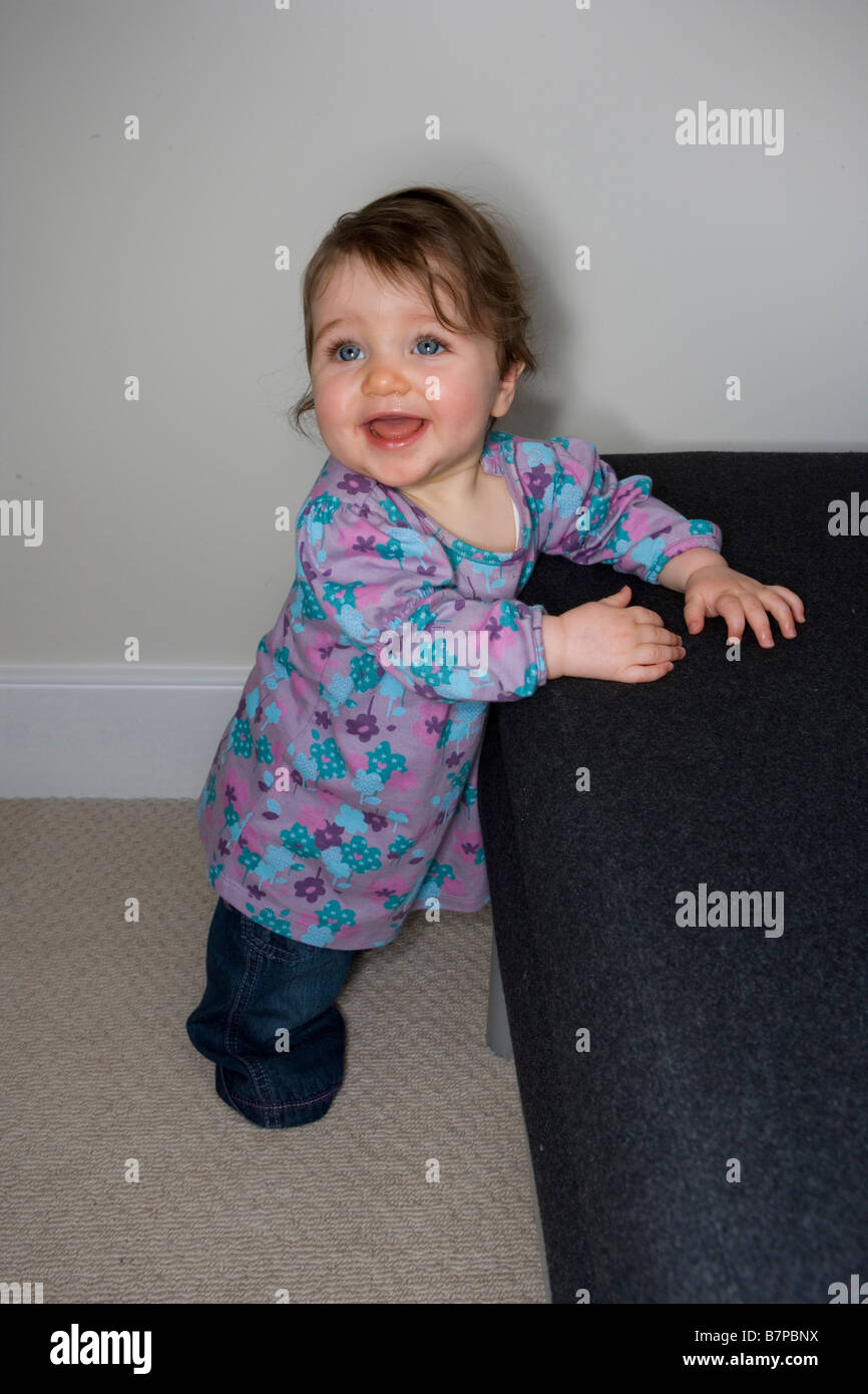A baby girl pulls herself up to stand Stock Photo Alamy