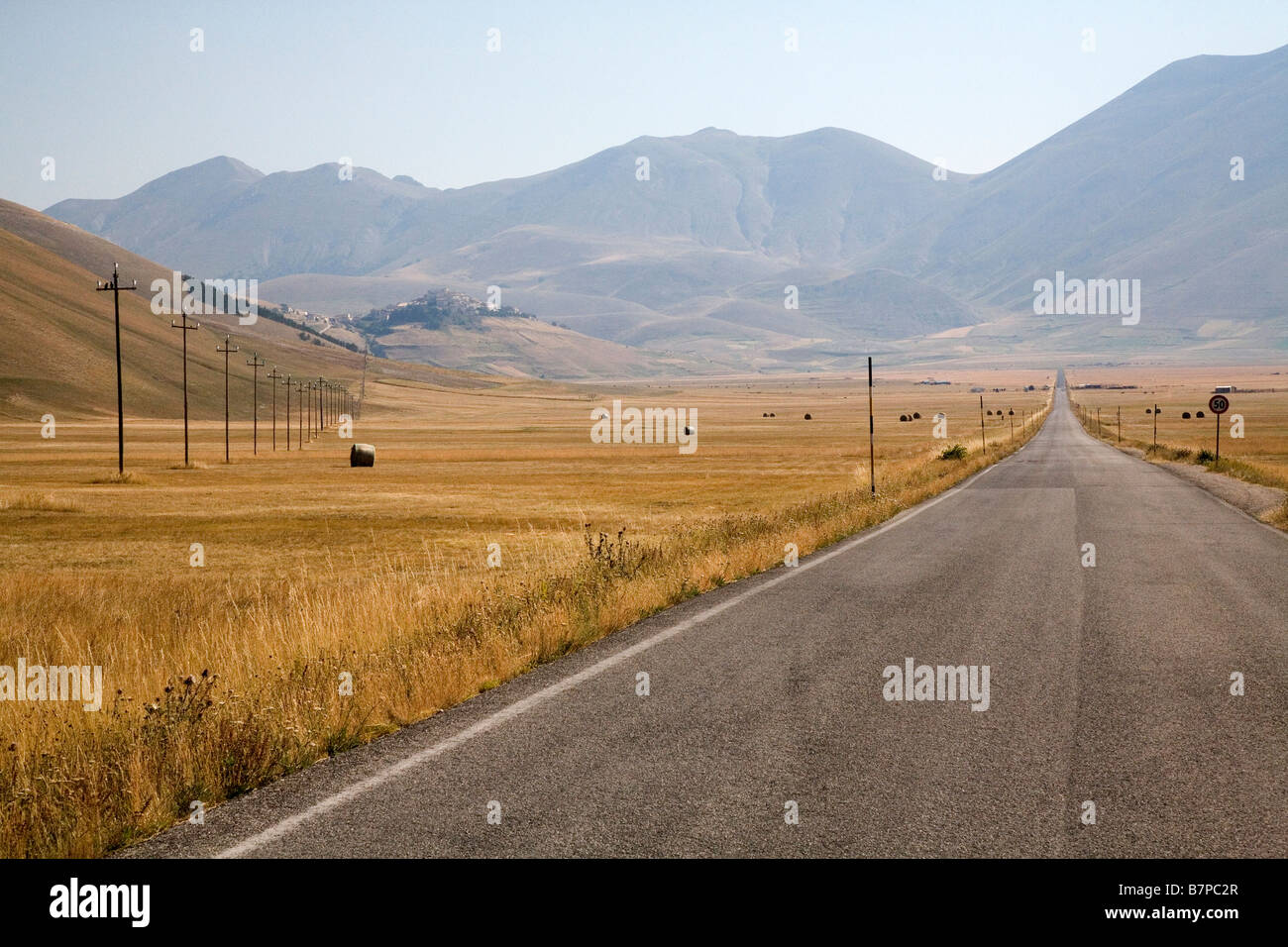 Road and utility poles in field near mountains Stock Photo - Alamy