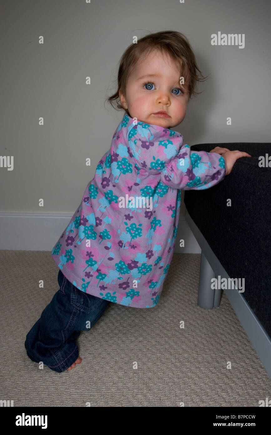 A eight month old baby girl pulls herself up to stand Stock Photo Alamy