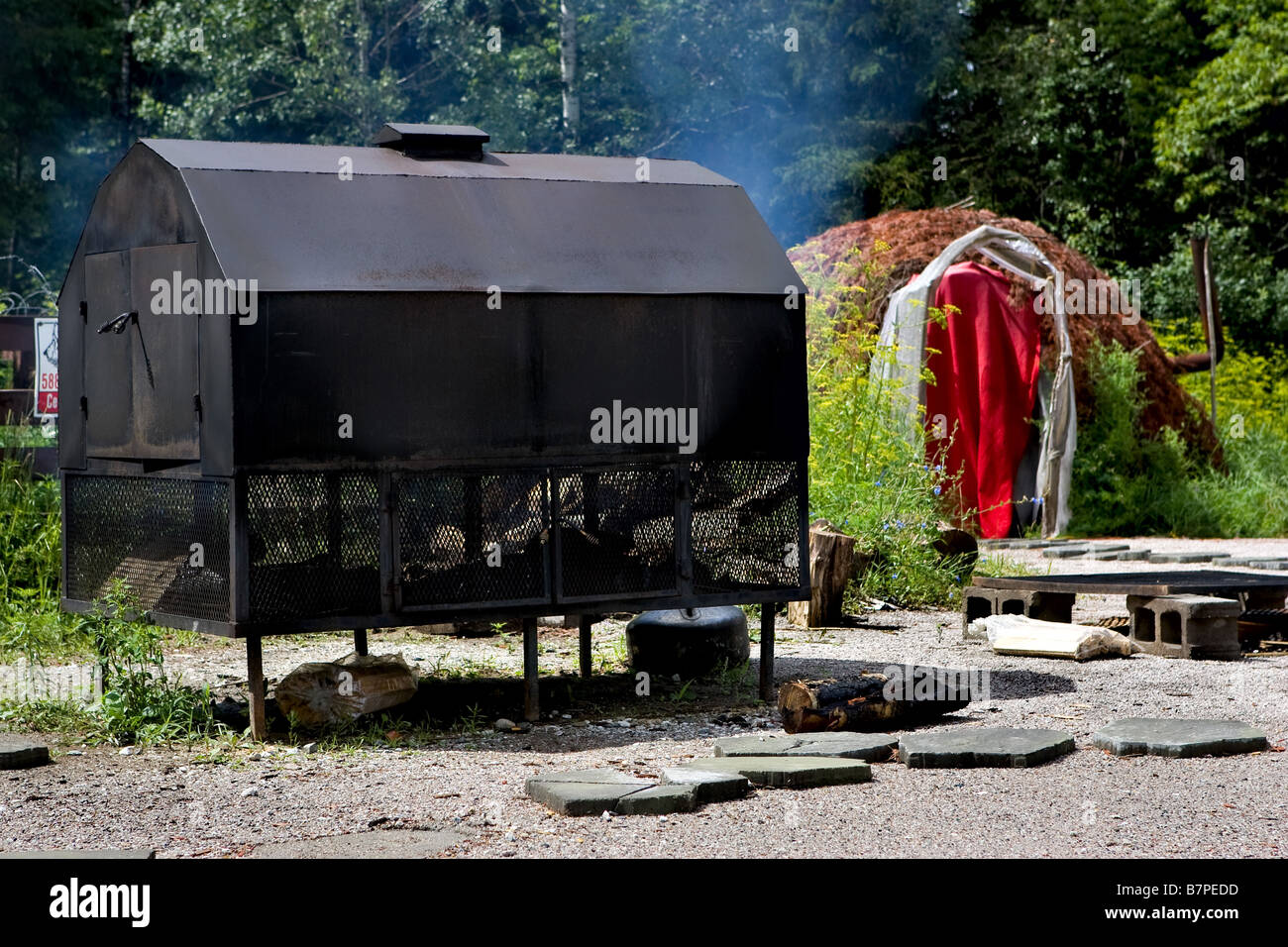 Meat is smoked in a big outdoor oven in a native camp in the Kitigan Zibi Algonquin in Quebec, Canada. Stock Photo