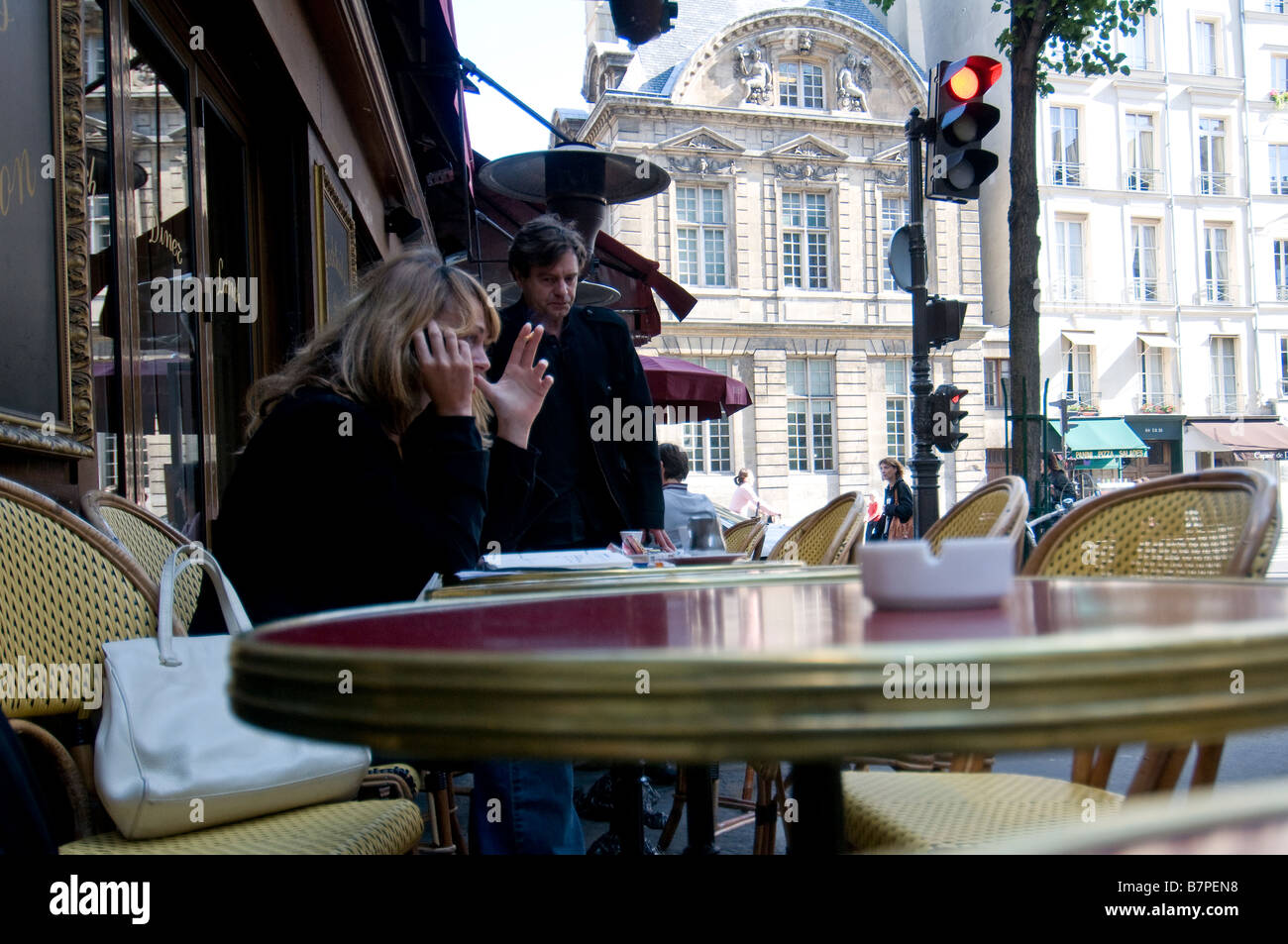 a woman is having coffee sitting on an outdoor table in a bar in the center of Paris Stock Photo