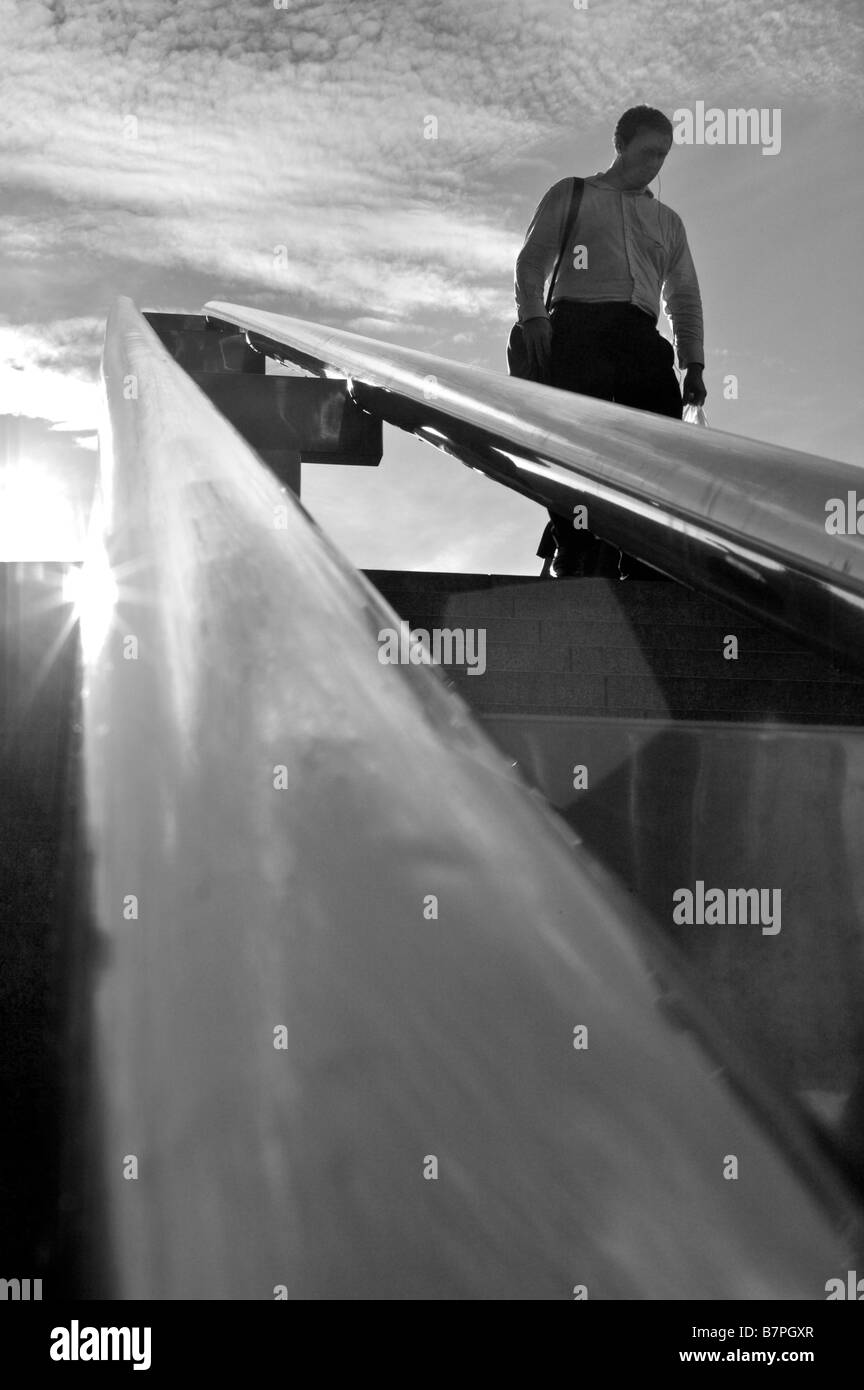 Black and white image of a business man walking down chrome staircase ...