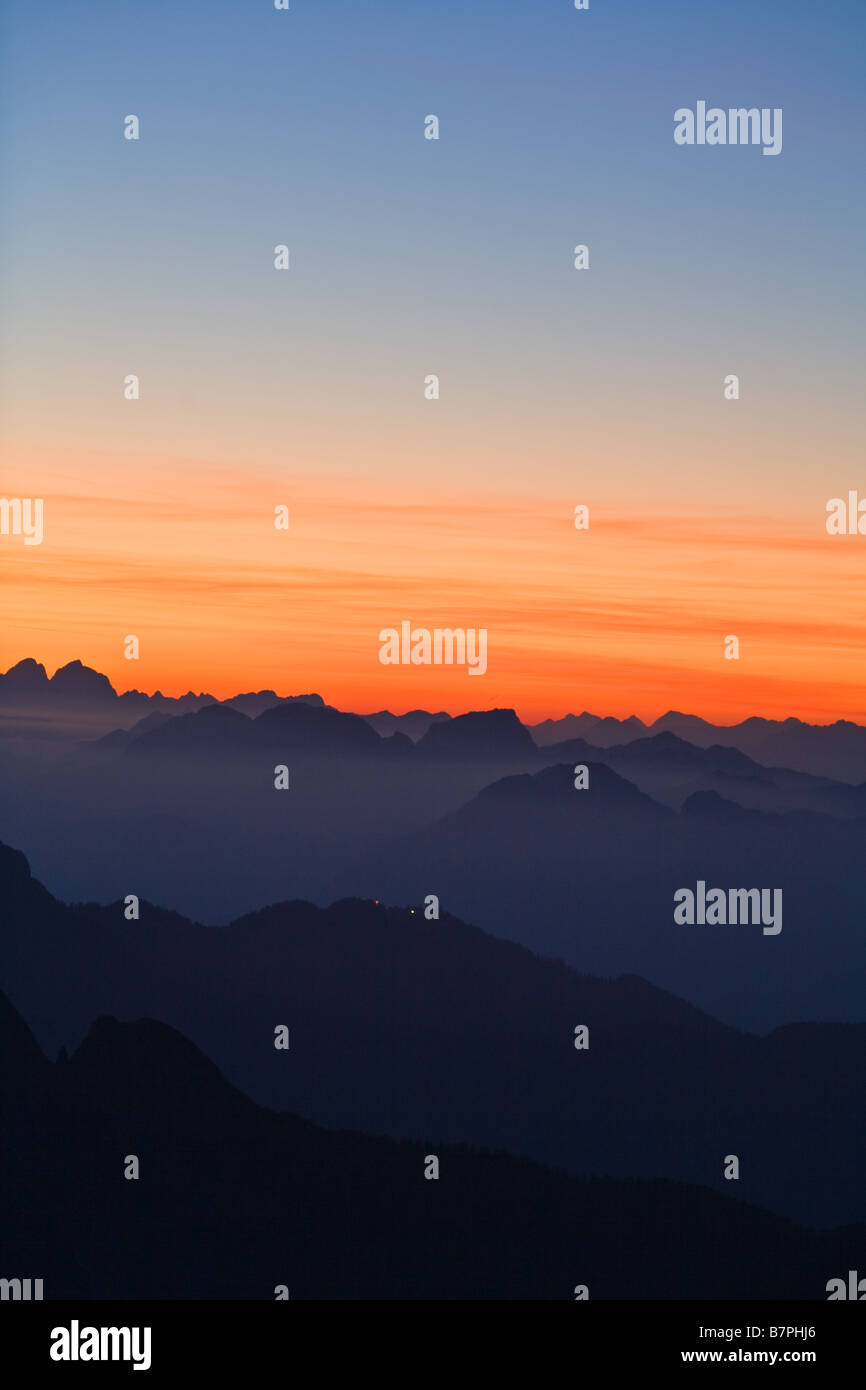 Julian Alps seen from Mangrt in Slovenia dark mountains to foreground with rich orange sunset to horizon and above Stock Photo