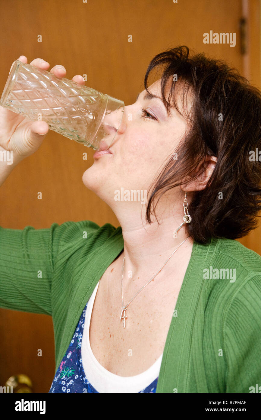 A woman drinking a glass of water Stock Photo